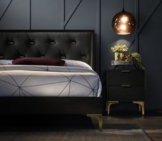 a bed with a black headboard and night stand next to it in a dark room