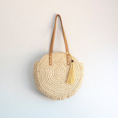 In Stock Fast Shipping From Los Angeles Carry your essentials in sweet, summery style with this Straw Circle Tote Handbag from Elena Handbags. This chic circular bag makes a great option for your warm weather errands like the farmer's market or thrifting, boasting an open-top design that provides quick and easy access to items inside. Double faux leather shoulder straps with whipstitch detailing add more texture to the look, while also providing comfortable carry over your shoulder as you go abo Casual Crochet Fringe Bag For Travel, Trendy Fringe Shoulder Bag For Vacation, Trendy Summer Crochet Bag With Tassels, Trendy Vacation Shoulder Bag With Fringe, Summer Beige Tassel Shoulder Bag, Casual Summer Shoulder Bag With Fringe, Trendy Crochet Travel Bag With Tassels, Daily Use Shoulder Bag With Tassels, Trendy Beach Straw Bag With Tassels