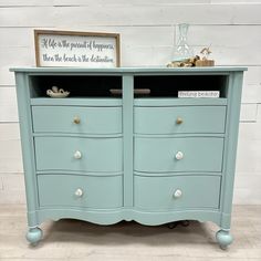 a blue dresser with two drawers and a sign on top