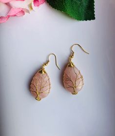 A pair of big charming teardrop-shaped green or pink hanging earrings, with gold wired tree of life wire wrapped artistically on the green or jade stones. They are so unique and eye-catching, hard to not notice when you wear them. Some highlights of these lovely gold family tree jade earrings are: *High-quality materials Quality green or pink jade stones, hand-wired in the tree of life wires. *Eye-catching design Simple and unique. The tree of life symbolizes the previous life, harmony, and fami Gold Wire Wrapped Teardrop Earrings For Gift, Pink Wire Wrapped Teardrop Earrings, Pink Teardrop Earrings Gift, Pink Teardrop Earrings With Natural Stones, Bohemian Teardrop Pink Earrings, Gold Teardrop Rose Quartz Jewelry, Pink Teardrop Bohemian Jewelry, Bohemian Pink Teardrop Jewelry, Handmade Pink Teardrop Crystal Earrings