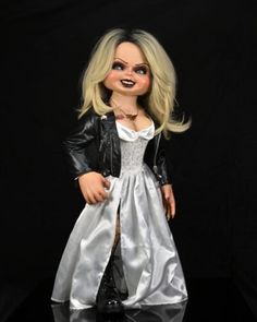 a doll dressed in a white dress and black leather jacket is posed for a photo