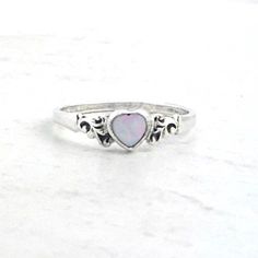 "Beautiful and simple, this sterling silver ring has a heart-shaped genuine opal. The natural Australian white opal heart has soft confetti flashes of color as it moves in the light. The hand carved heart shaped opal gemstone is just 5mm. On either side of the opal heart are etched filigree scrolls. Handmade to order in the USA. Please message us if you would like a size not offered. Dimensions: Opal 5mm. Total length of the filigree and opal heart is 1/2\" inch." Silver Heart-shaped Birthstone Ring, White Heart-shaped Birthstone Ring, White Sterling Silver Heart Ring With Birthstone, Opal Heart Ring, Minimalist Silver Ring, Natural Opal Ring, White Opal Ring, Carved Heart, Zierlicher Ring