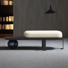 a black and white bench sitting in front of a book shelf with books on it