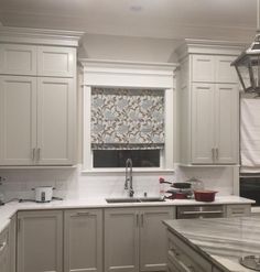 a kitchen with white cabinets and gray counter tops is seen in this image from the front view