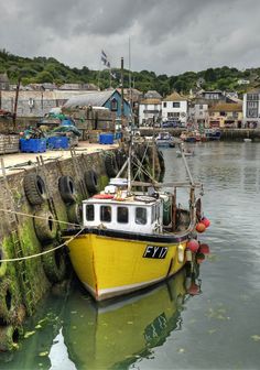 a yellow and white boat tied to a dock