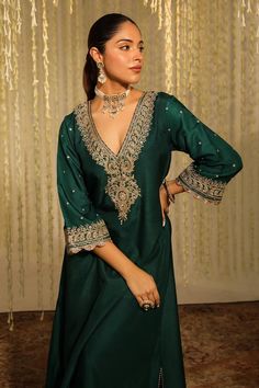 Emerald green long kaftan with placed thread embroidered paisley motifs embellished by sequins. Comes with matching doghri salwar.
Components: 2
Pattern: Embroidered
Type Of Work: Thread, Sequin
Neckline: V-neck
Sleeve Type: Three quarter
Fabric: Silk Dupion
Color: Emerald Green
Other Details: 
Flared silhouette
Occasion: Sangeet,Mehendi and Haldi - Aza Fashions Traditional V-neck Semi-stitched Salwar Kameez, Eid V-neck Kurta With Intricate Embroidery, Semi-stitched V-neck Dress For Festive Occasions, Semi-stitched V-neck Festive Dress, Elegant V-neck Kurta For Festive Occasions, Elegant V-neck Kaftan For Festive Occasions, Festive V-neck Salwar Kameez With Zari Work, Green V-neck Kurta With Resham Embroidery, Traditional Green V-neck Tunic