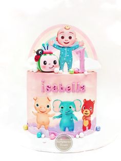 a pink cake with animals on it and the number one is spelled in spanish for an infant's first birthday