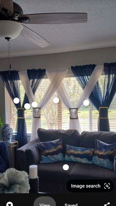 a living room filled with furniture and windows covered in blue draping, along with white curtains