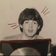 an old black and white photo of a young man holding a record