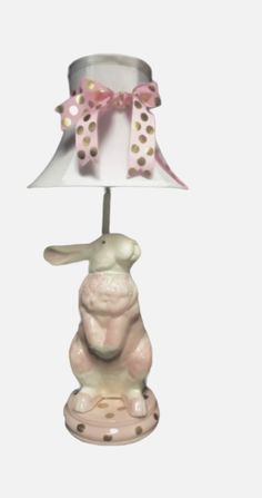 a lamp with a pink and white bunny sitting on it's side, next to a polka dot lampshade