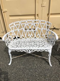 a white metal bench sitting on top of a cement floor next to a wall and door