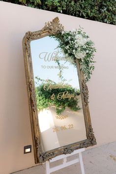 a mirror that is sitting on top of a stand with flowers in front of it