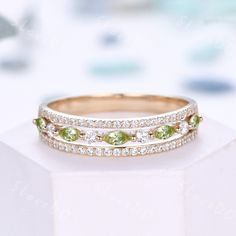 two wedding bands with green and white stones on top of each other in front of a white background