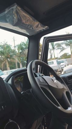 the inside of a truck with its steering wheel and dash light on, as seen through the windshield