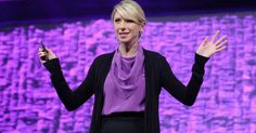 a woman standing in front of a purple background holding her hands up to the side