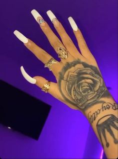 a woman's hand with white nails and tattoos on her arm, in front of a purple background