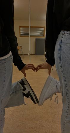 two people holding hands in the shape of a heart with their feet crossed and one person wearing sneakers