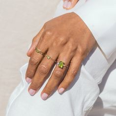 a woman's hand with two gold rings on her left and one green ring on her right