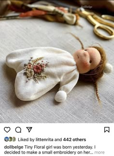 a doll laying on top of a table next to scissors