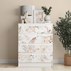 a white dresser sitting next to a potted plant