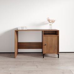 a wooden desk with a vase on top of it and a white wall in the background