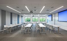 an empty conference room with tables and chairs in front of a large flat screen tv