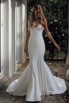 a woman in a white wedding dress standing outside