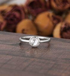 a white diamond ring sitting on top of a wooden table next to some oranges