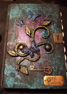 an altered book with butterflies and keys on it's cover is sitting on a table