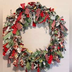 a christmas wreath made out of old clothes hanging on the wall in front of a white wall