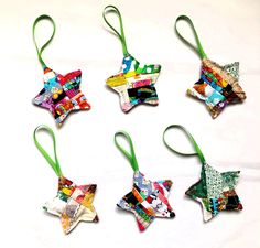 six ornaments are arranged in the shape of stars on green ribboned ends, with different patterns and colors