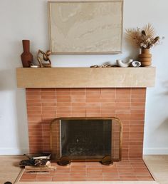 a fire place in a living room with a painting on the wall and other items around it