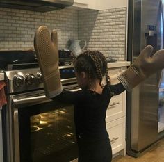 a girl with her hands up in front of an oven