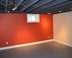 an empty room with red walls and white trim on the ceiling is lit by recessed lights