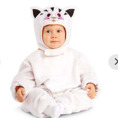 a baby wearing a cat costume sitting on the ground