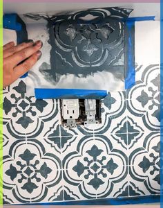 a person is painting a wall with blue tape and some black and white designs on it