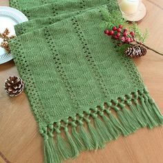 a green table runner on a wooden table with pine cones, candles and other holiday decorations