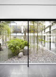 an open glass door leading to a garden with rocks and trees in the foreground