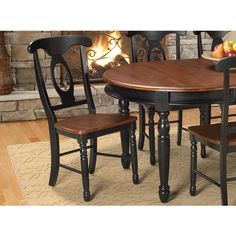 a dining room table with four chairs and a fire place in the fireplace behind it