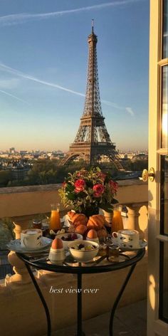 the view of the eiffel tower from an outside balcony with breakfast on it