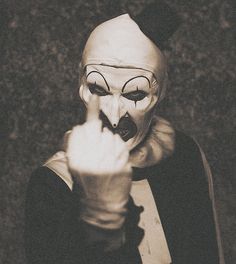 a person wearing a creepy mask and pointing to the side with their finger in front of them