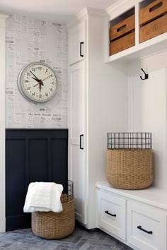 there is a clock on the wall next to some white cabinets and drawers in this room