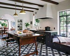 a kitchen with black and white tile flooring next to a dining room table in front of a window