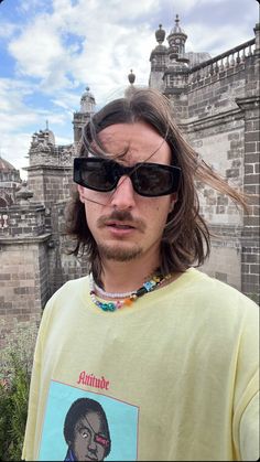 a man with long hair and sunglasses standing in front of a castle