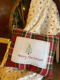 a christmas pillow sitting on top of a wooden chair next to a white crocheted blanket