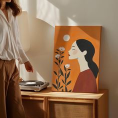 a woman standing in front of a painting on a table next to a record player