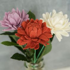 three different colored flowers in a glass vase