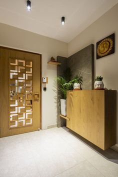 a room with a large wooden door and some plants on the shelf next to it