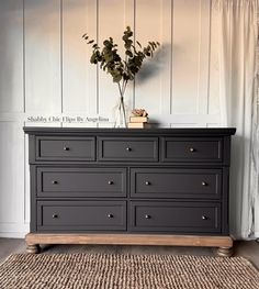 a black dresser with gold knobs and drawers in front of a white paneled wall