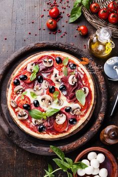 a pizza sitting on top of a pan covered in toppings next to tomatoes and mushrooms